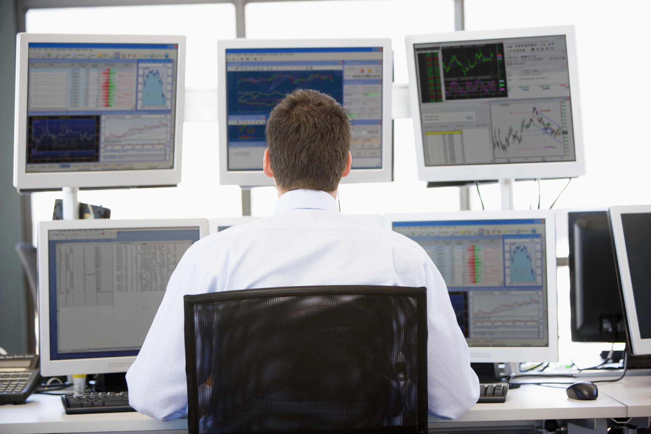 Financial analyst reviewing market information across multiple screens